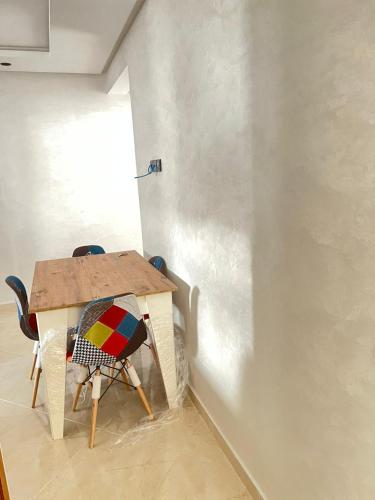 une table avec deux chaises assises à côté d'un mur dans l'établissement Adorable Appartement meublé en plein centre ville, à Kenitra