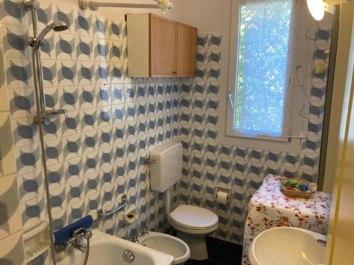 uma casa de banho com um lavatório, um WC e uma janela. em Casa di Ro - coloratissima a 300 metri dal mare em San Bartolomeo al Mare