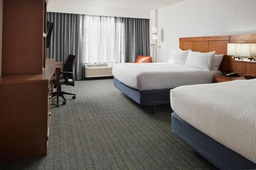 シャーロッツヴィルにあるCourtyard by Marriott Charlottesville - University Medical Centerのベッド2台とデスクが備わるホテルルームです。
