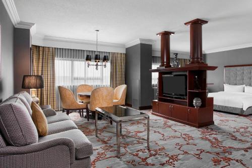 a living room with a couch and a television and a bed at Teaneck Marriott at Glenpointe in Teaneck