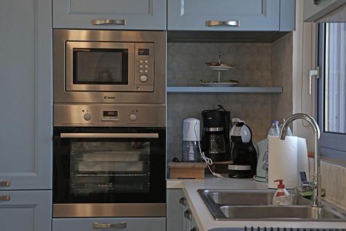 a kitchen with a stove and a sink and a microwave at Ciel Villa in Kalyves