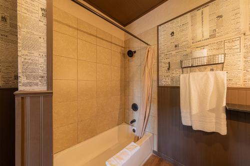 a bathroom with a shower and a tub with a towel at -Pet Friendly- Miners Cabin #6 - King Bed with Private Balcony in Tombstone