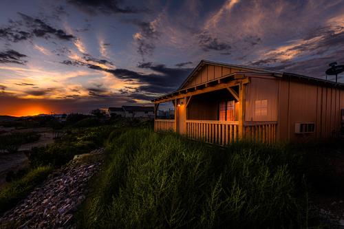 a house on a hill with a sunset in the background at -Pet Friendly- Miners Cabin #6 - King Bed with Private Balcony in Tombstone