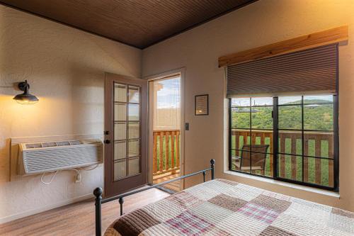 a bedroom with a bed and a balcony with a window at -Pet Friendly- Miners Cabin #6 - King Bed with Private Balcony in Tombstone