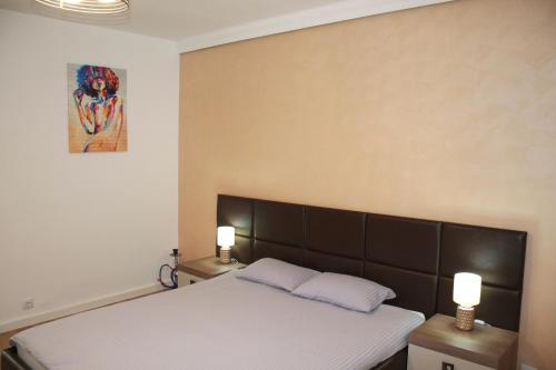 a bedroom with a bed with two night stands and two lamps at Studio Dristor - foarte curat si frumos in Bucharest