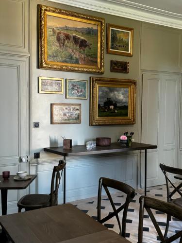 Les Deux Marguerite في ألونسون: غرفة بها لوحات على الحائط وطاولات وكراسي