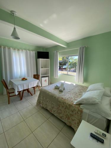 a bedroom with a bed and a table and a window at Hotel Enseada in São Francisco do Sul