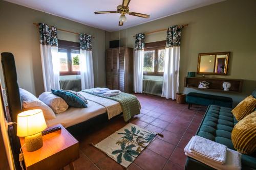 a bedroom with a bed and a couch and windows at The Village House in Volos