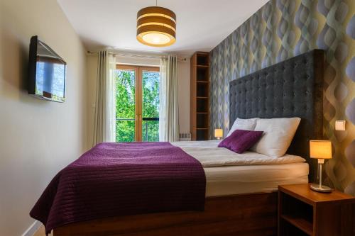 a bedroom with a purple bed with a window at Apartament Helios in Jastrzębia Góra