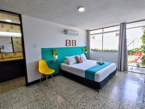 a bedroom with a bed and a yellow chair at Bona Vida Hotel in Ríohacha