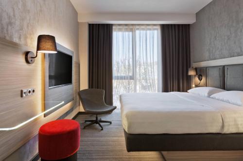 a hotel room with a bed and a chair and a television at Moxy Tbilisi in Tbilisi City