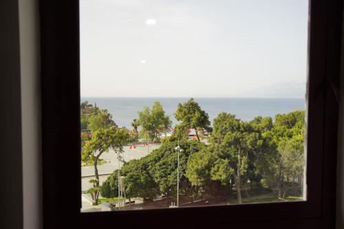 a window view of a park with trees and the ocean at Royal Homes 402 in Antalya