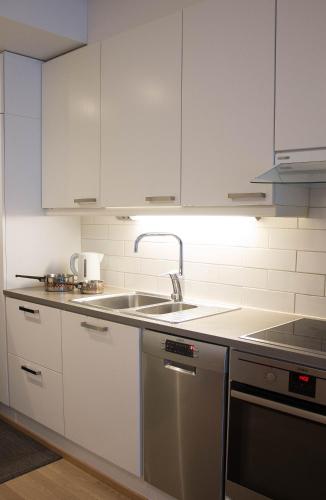 a kitchen with white cabinets and a sink at Kotiyksiö Center in Lahti