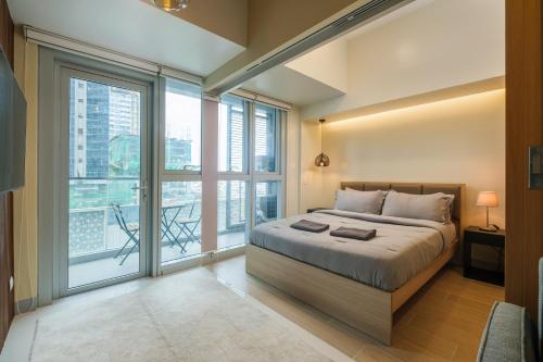 een slaapkamer met een bed en grote ramen bij Uptown Parksuites Modern Room in Manilla