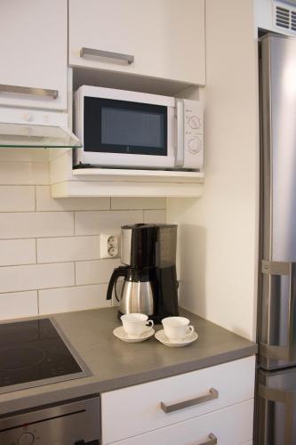 a kitchen with a microwave and two cups on a counter at Kotiyksiö Center in Lahti
