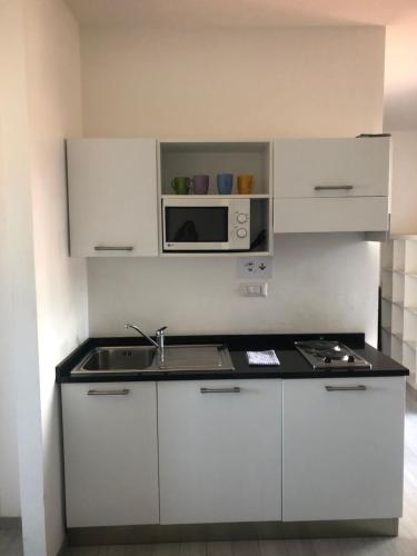 a white kitchen with a sink and a microwave at Aurasol Alghero in Alghero