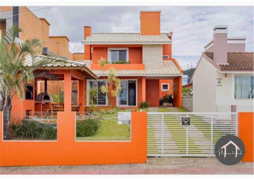 an orange house with a fence in front of it at Casa em Garopaba - Piscina - Forno para pizza - Ar condicionado - 3 quartos in Garopaba