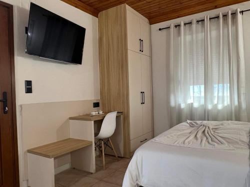 a bedroom with a bed and a desk and a television at Up To The Sea in Agios Ioannis Kaspaka
