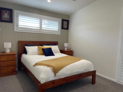 a bedroom with a bed with two night stands and a window at 1 Tree Escape in Wooli