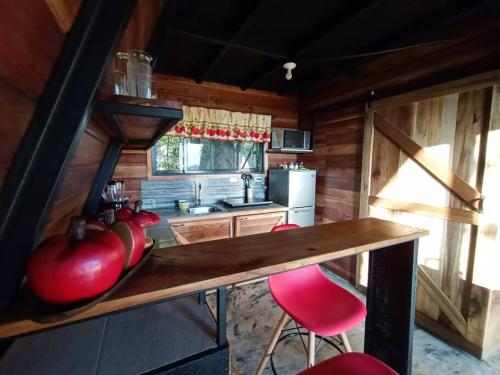 uma cozinha com uma mesa e cadeiras vermelhas num quarto em Casa del Árbol (A-Frame) - Ágape del Bosque em Monteverde