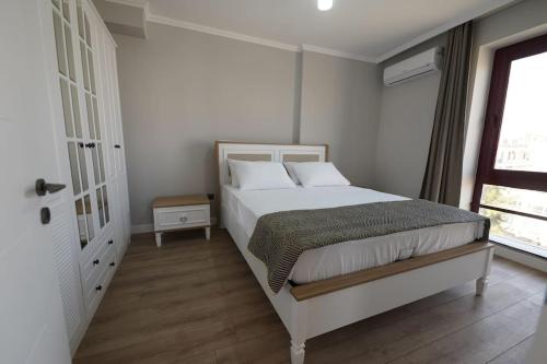 a white bedroom with a bed and a window at Royal Homes 404 in Antalya