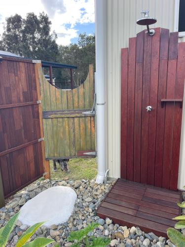 a door to a house with a dog standing next to it at 1 Tree Escape in Wooli
