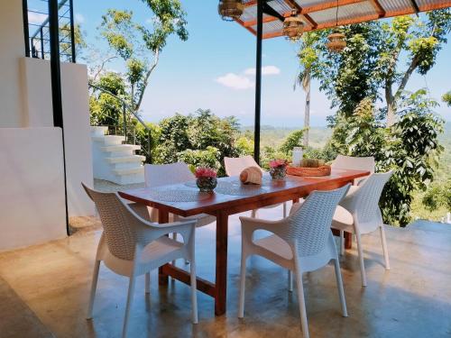 a dining room with a wooden table and white chairs at Las Terrazas de Barili Private Resort in Barili