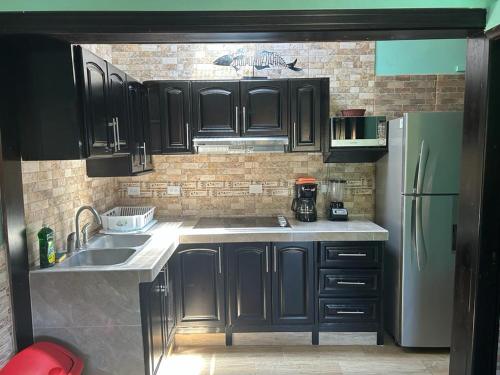 eine Küche mit schwarzen Schränken und einem weißen Kühlschrank in der Unterkunft Villas Paraíso Jacó B20 in Jacó