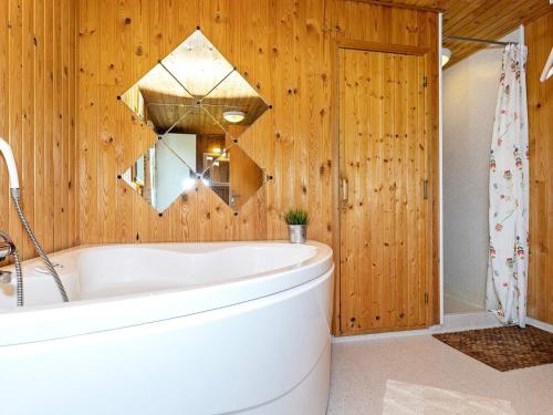Lild StrandにあるThree-Bedroom Holiday home in Frøstrup 1の白いバスタブと木製の壁が備わるバスルーム