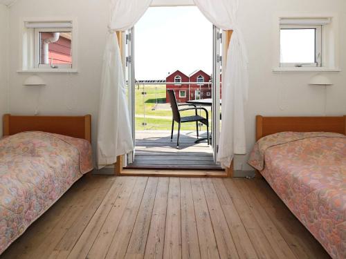 Øster HurupにあるHoliday Home Havblik IIのベッド2台 パティオに面したドア付きの客室です。