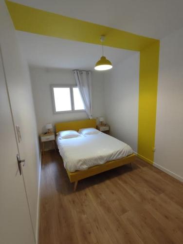 - une chambre avec un lit et un mur jaune dans l'établissement Appartement Le Secret 140m2, Proche Sanctuaires, Climatisé, à Lourdes