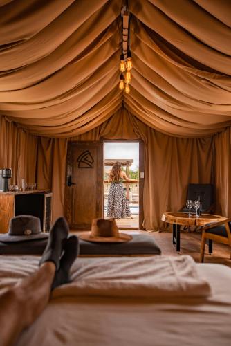 a woman walking into a tent with two beds at Indomito Resort & Hotel Boutique in Valle de Guadalupe