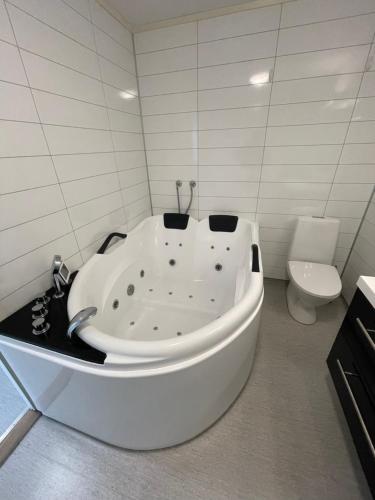 a white bath tub in a bathroom with a toilet at Lovely apartment with parking in the heart of city in Lillehammer