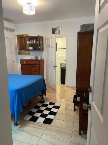 a kitchen with a blue bed and a checkered floor at Centrally Located Room - 5 in Port Antonio