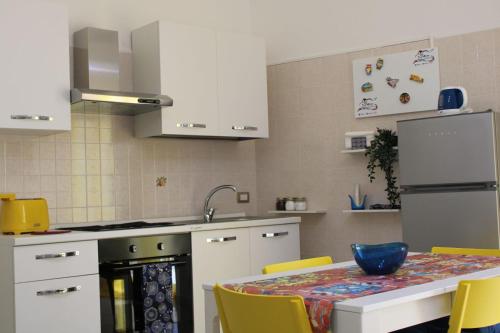 馬里納－迪拉古薩的住宿－Sikelia，厨房配有带黄椅的桌子和冰箱。