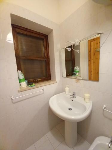 baño con lavabo, espejo y ventana en Villetta Elaion, en Scario