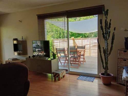 a living room with a television and a deck with a table at Location appartement in Boucau