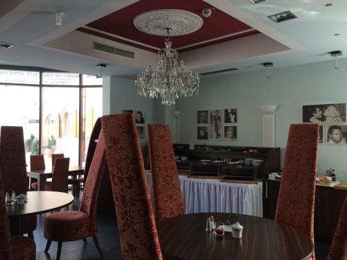 a dining room with a table and chairs and a chandelier at CineHotel Maroni in Zirndorf