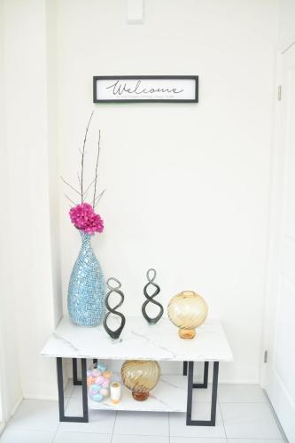 a white console table with a blue vase on it at PARADISE VILLa Bowmanville in Bowmanville