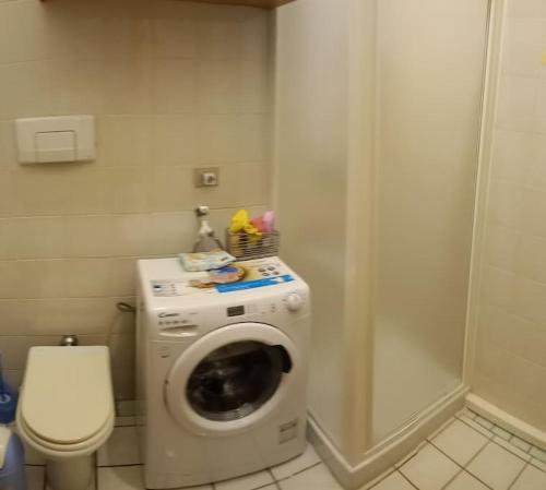 a bathroom with a washing machine and a toilet at Appartamente moderno e accessoriato. in Pula