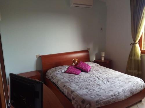 a bed with pink pillows and a teddy bear on it at Appartamente moderno e accessoriato. in Pula