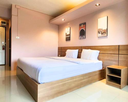 a bedroom with a large bed with a wooden headboard at AIRBEST Gemtree Lampang Hotel in Lampang