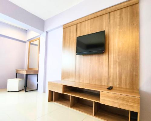 a living room with a tv on a wooden wall at AIRBEST Gemtree Lampang Hotel in Lampang