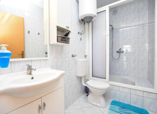ein weißes Bad mit einem Waschbecken und einem WC in der Unterkunft Apartments Tonja in Primošten