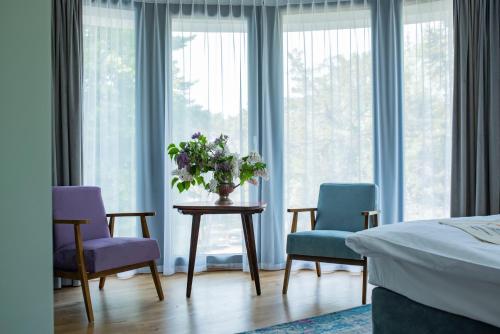 Ohana Space w Juracie في يوراتا: غرفة نوم بثلاث كراسي وطاولة مع إناء من الزهور