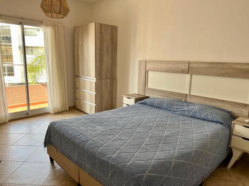 1 dormitorio con 1 cama con edredón azul en Depto 8 - Villa Carlos Paz en Villa Carlos Paz