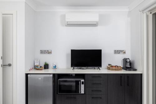 a kitchen with a counter with a tv and a microwave at Whale Studio Suite in Anna Bay