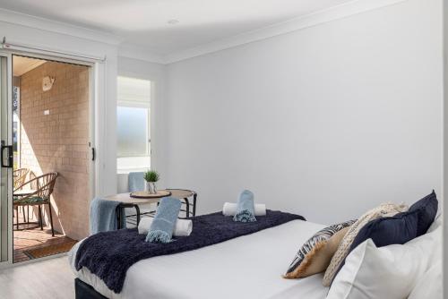 Un dormitorio blanco con una cama grande y una mesa en Whale Studio Suite, en Anna Bay