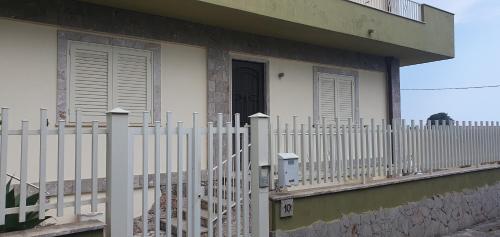 a white fence in front of a house with a door at Agape casa vacanze in Giardini Naxos