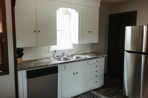 a kitchen with white cabinets and a sink and a refrigerator at Bluebird Cottage, walking distance to fairgrounds in Hutchinson